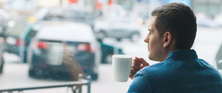 Man drinking coffee looking out window
